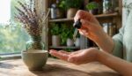 A hand delicately pours a few drops of CBD oil, in a peaceful and soothing indoor atmosphere.