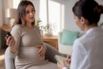 Schwangere Frau im Gespräch mit einer Hebamme